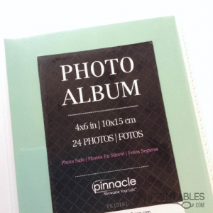 A close-up of a photo album cover, displaying text that reads "PHOTO ALBUM", "4x6 in | 10x15 cm", "24 PHOTOS | FOTOS", "Photo Safe | Photos En Sûreté | Fotos Seguras", and the brand "pinnacle".