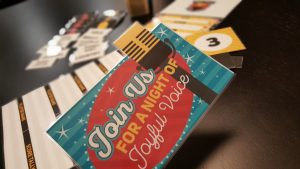 A colorful card with a microphone design and the text "Join Us FOR A NIGHT OF Joyful Voice" is prominently displayed, with other game cards labeled "PLAYER NAME," "SCORE TALLY," and a yellow card with the number "3" visible in the background.