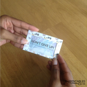 A person's hands hold a small badge or card holder with a colorful border of animal faces, displaying text that reads "2017 DON'T GIVE UP! CONVENTION OF JEHOVAH'S WITNESSES" and lines for name and congregation.