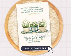 A greeting card featuring a Bible verse from 2 Corinthians 1:3-4, an illustration of three potted plants with white flowers, one pot labeled "GET WELL SOON," and text wishing comfort and healing, with a "DIGITAL DOWNLOAD" button at the bottom, all placed on a woven tray.
