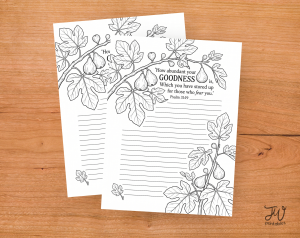Two white sheets of paper with black and white line art of fig branches and leaves, featuring the Bible verse "How abundant your GOODNESS is, Which you have stored up for those who fear you. Psalm 31:19" and a "JW Printables" logo, are displayed on a wooden surface.